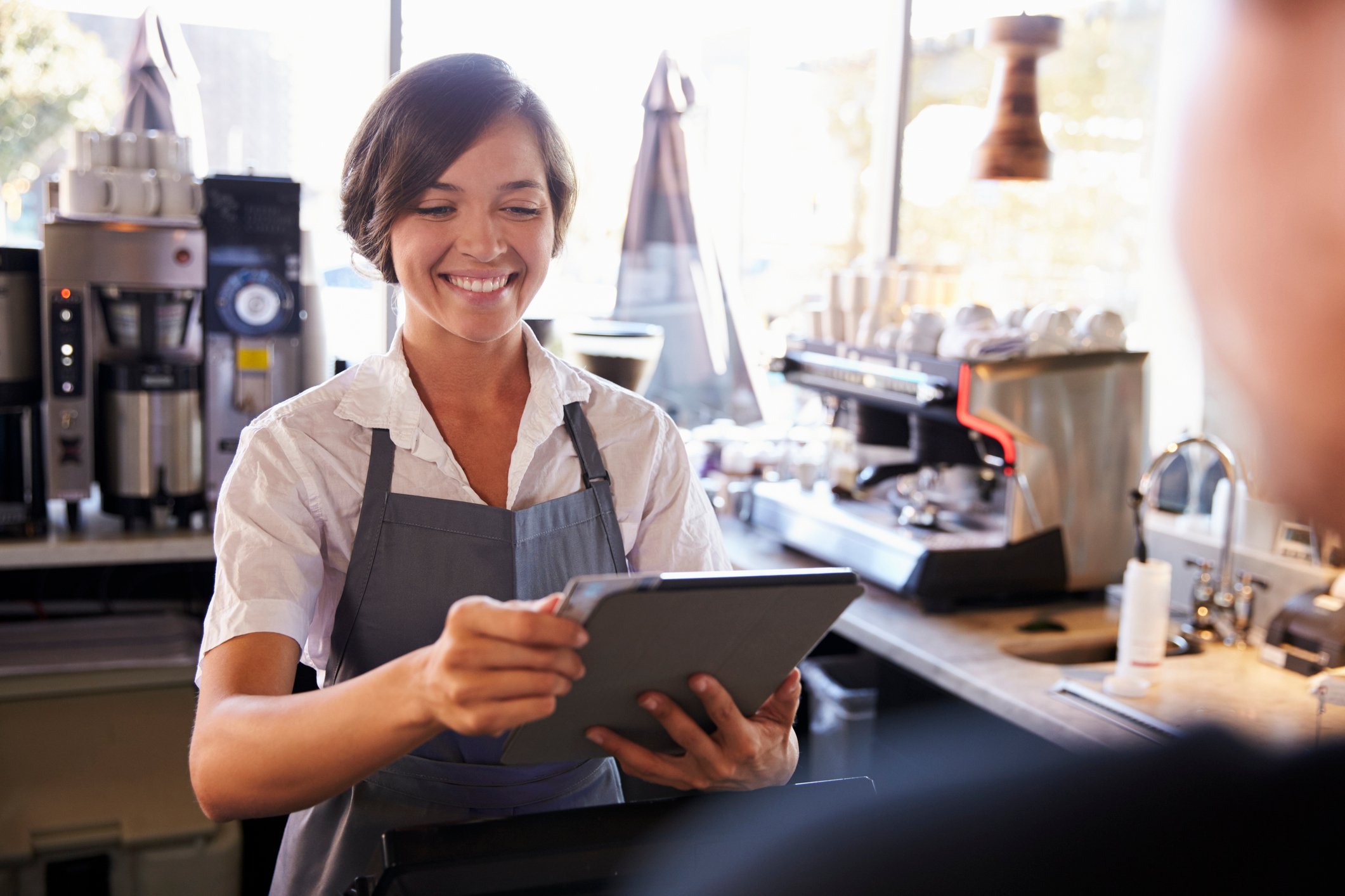 A smiling barista uses a tablet at point of sale.