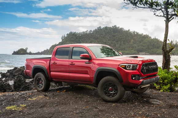 A red Toyota Tacoma 4x4 parked next to a lake. 