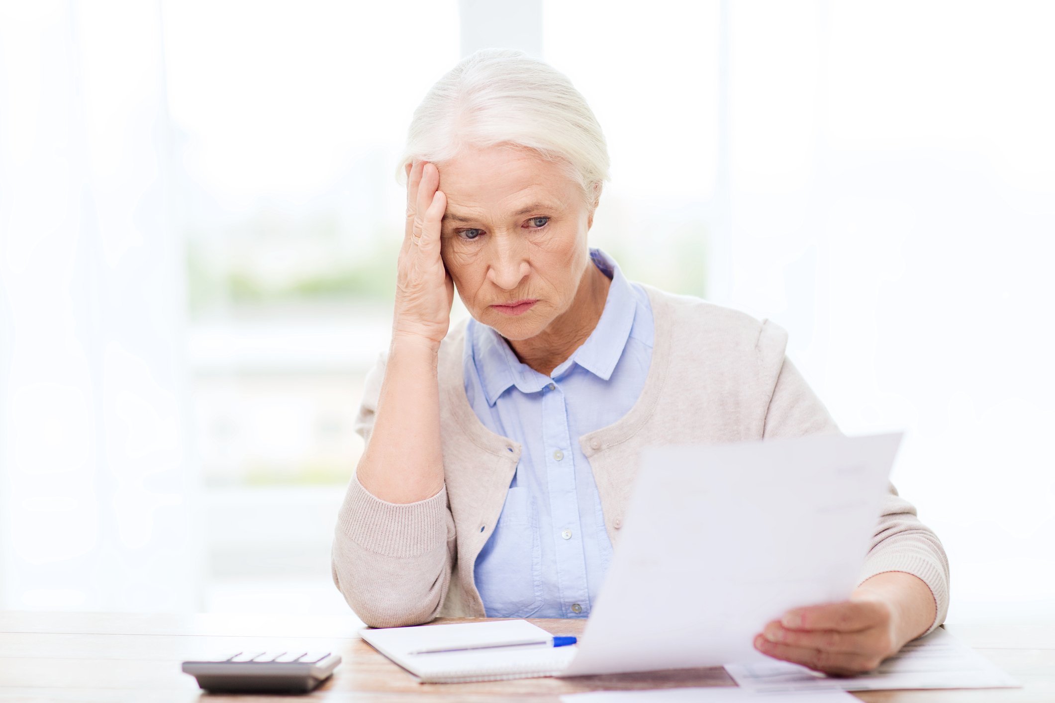 Senior woman holding her head while looking at a document