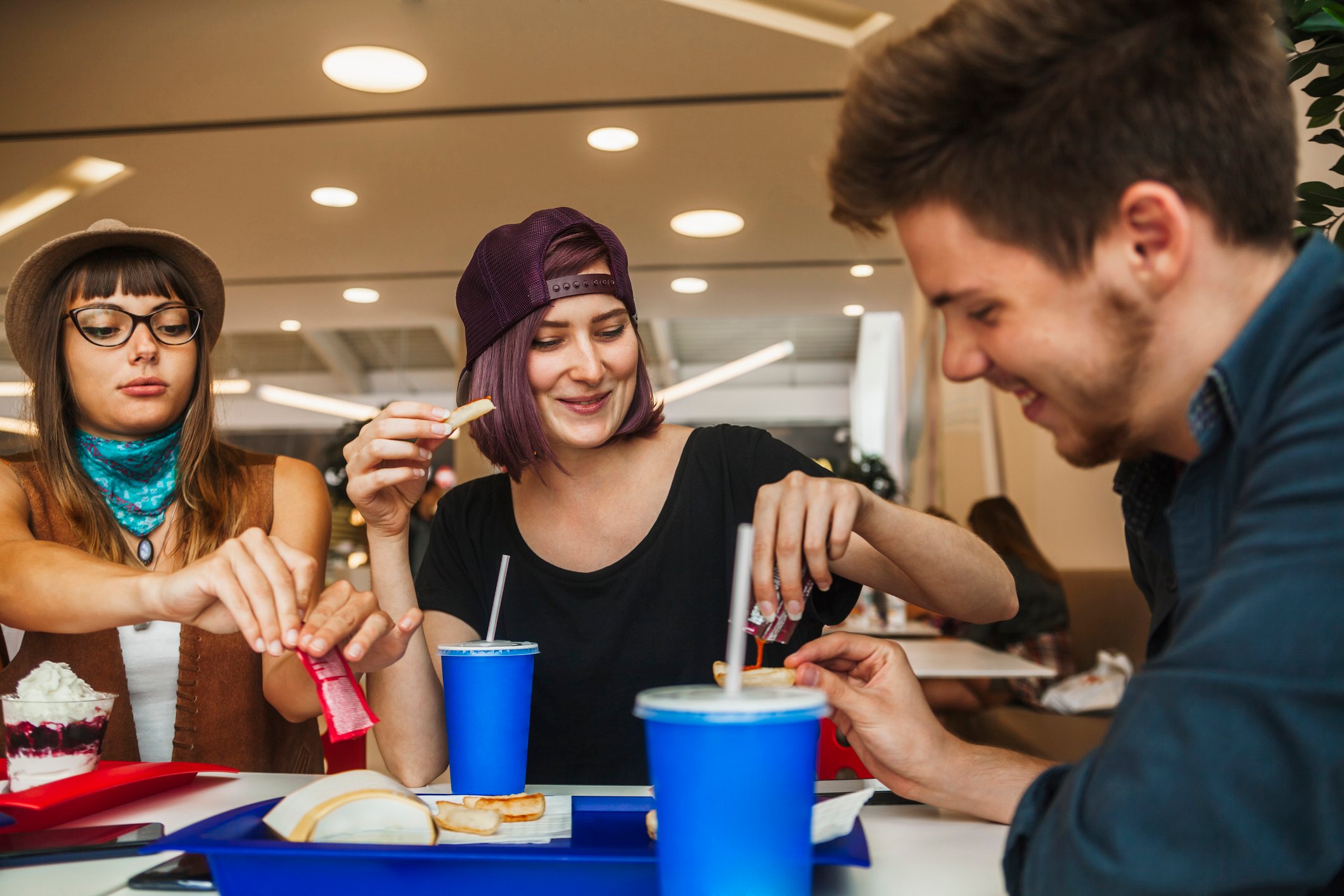 Three friends eating at a shopping mall food court