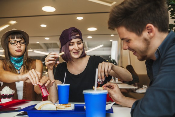 Three friends eating at a shopping mall food court