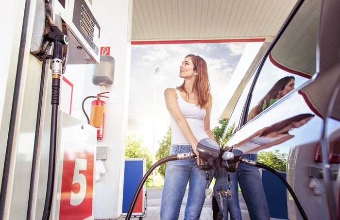 A woman pumps gas at a station