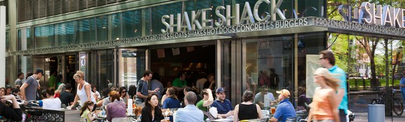 A crowd sitting at the patio outside of a Shake Shack.