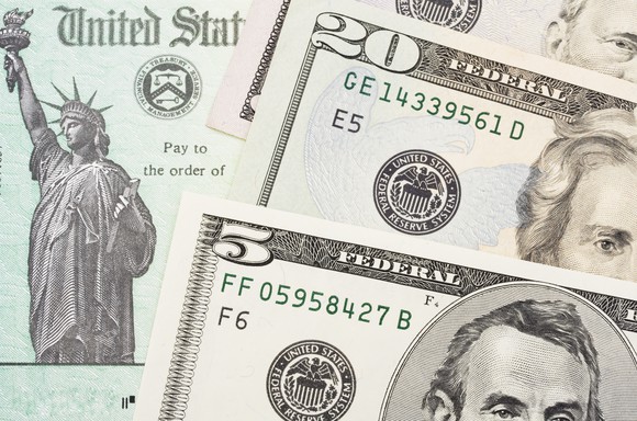 US tax refund check with money laid out on top of it.