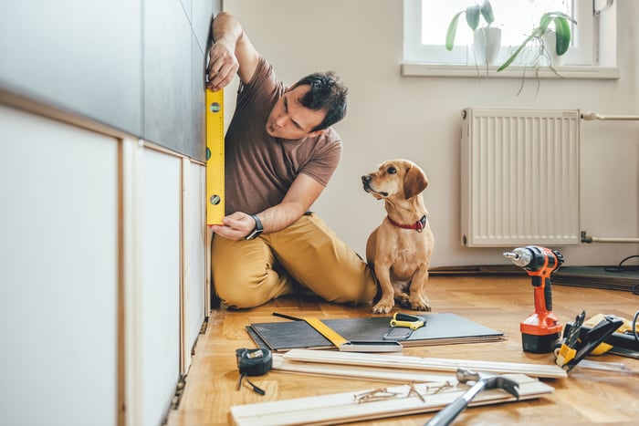 Man and dog measuring to see if a wall is level