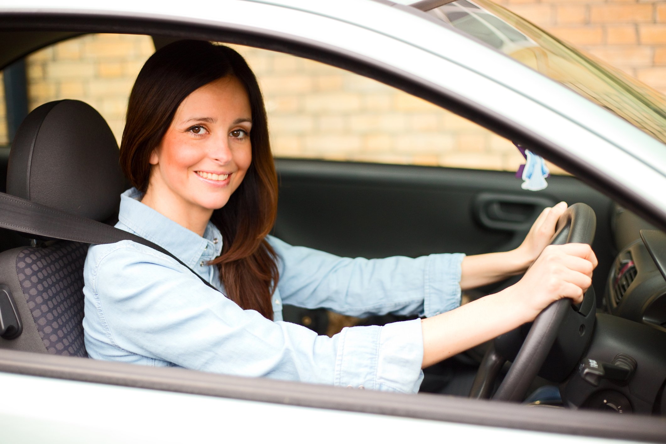 A woman is seen driving a car.