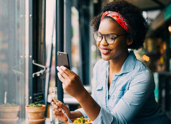 A smiling woman uses a smartphone.