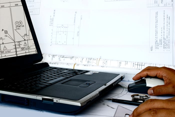 A man working on manufacturing drawings on a laptop.