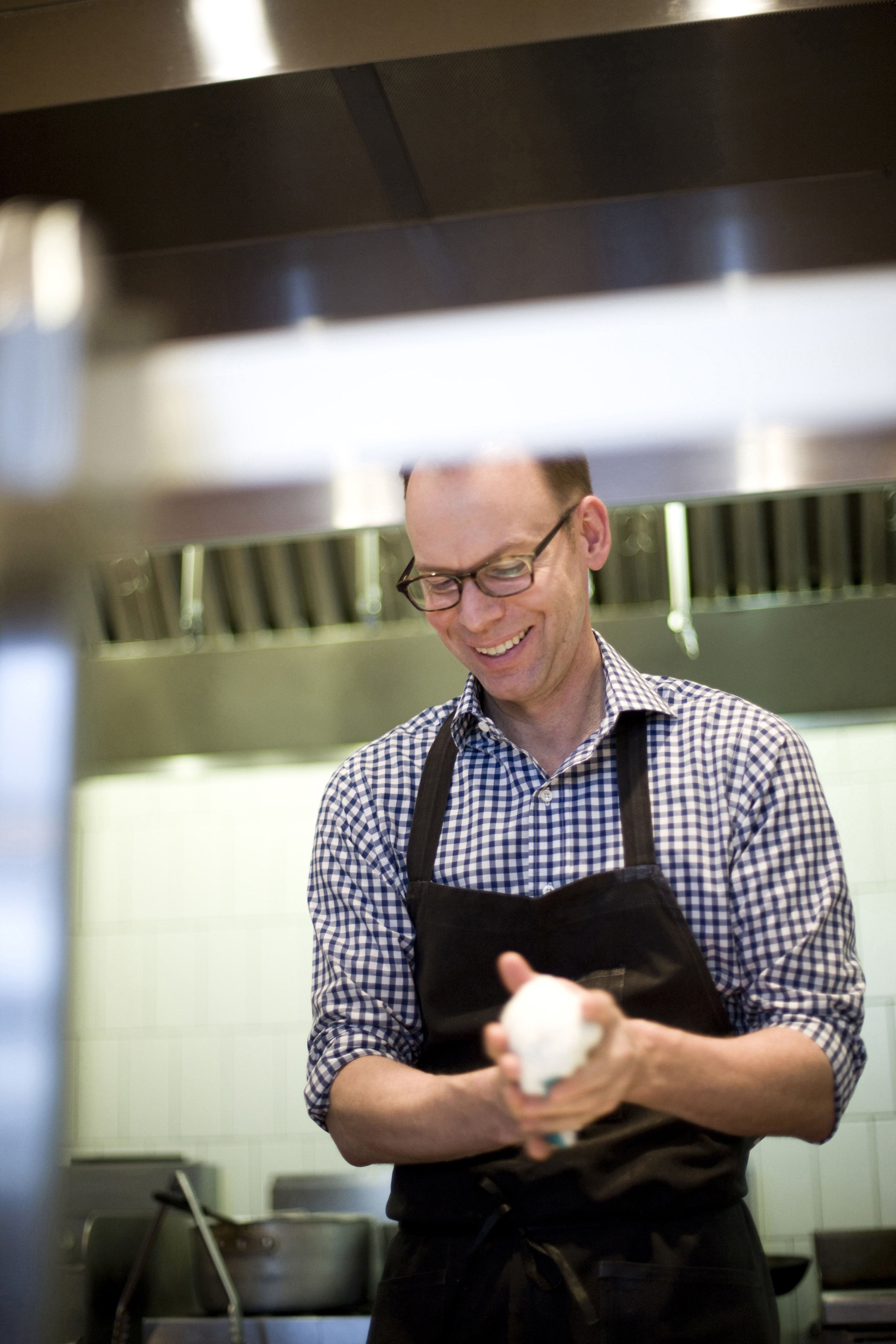 Steve Ells stands in a restaurant kitchen holding an object in his hands