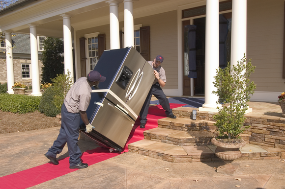 Two men delivering a heavy home appliance.