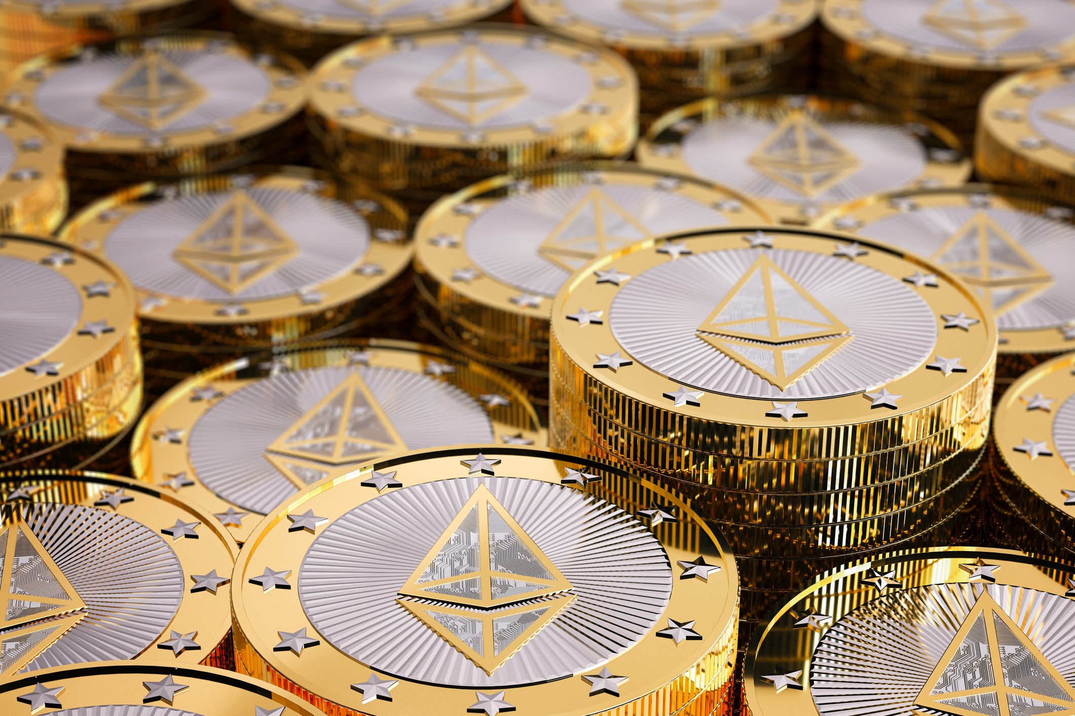 Numerous shiny silver-and-gold colored coins with the Ethereum symbol on them.