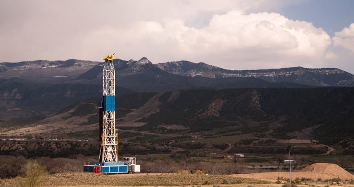 Drilling rig at work with mountains in background.