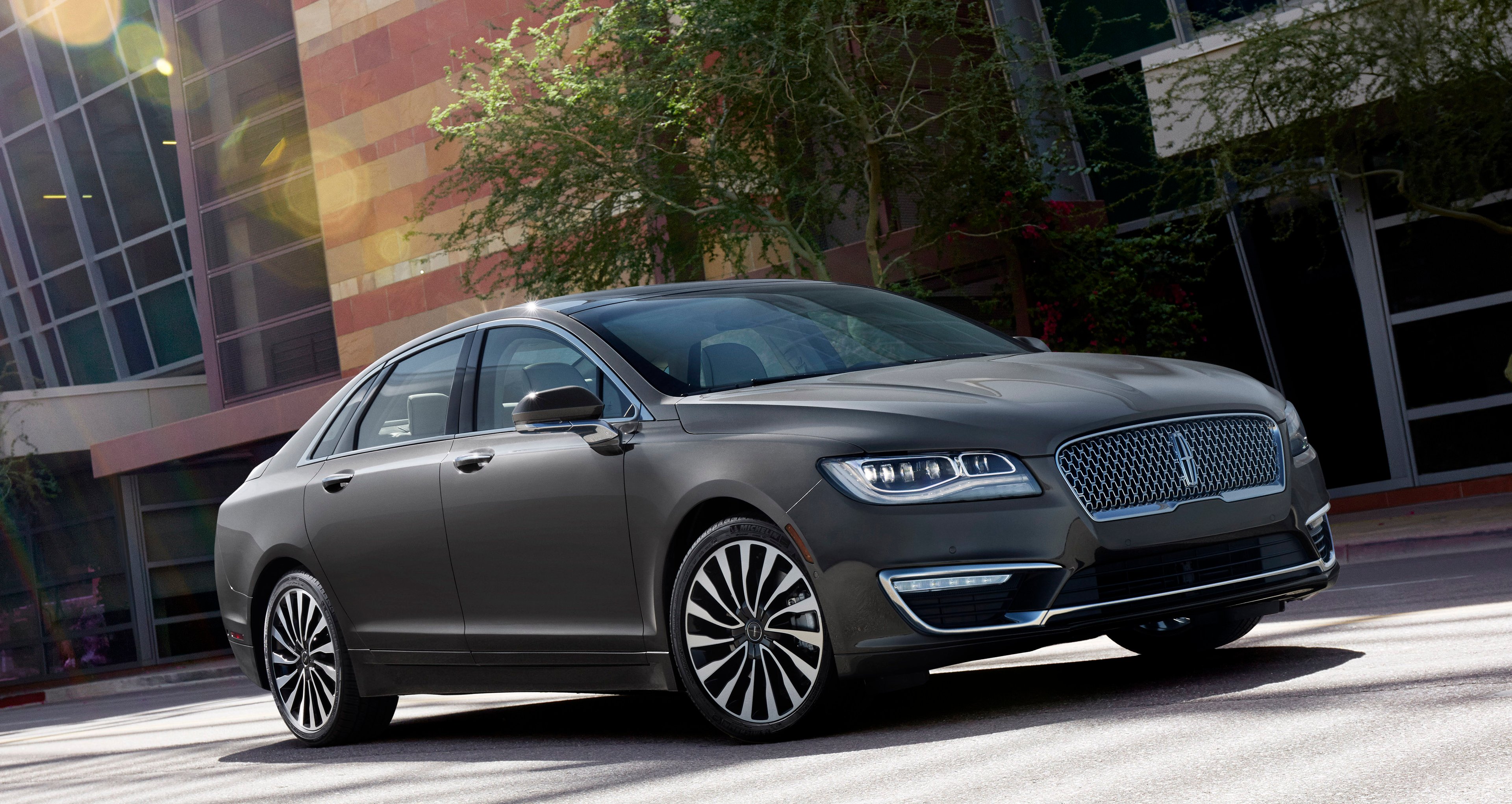 A dark gray 2017 Lincoln MKZ midsize sedan, parked outside an office building.