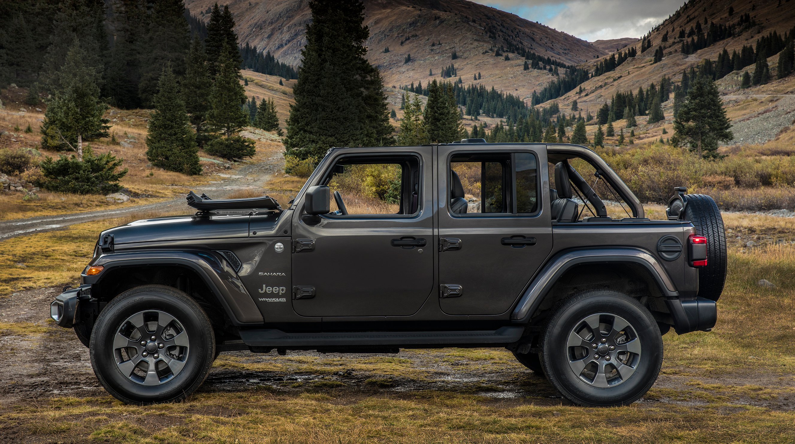 A green 2018 Jeep Wrangler Unlimited Sahara near a mountain road.