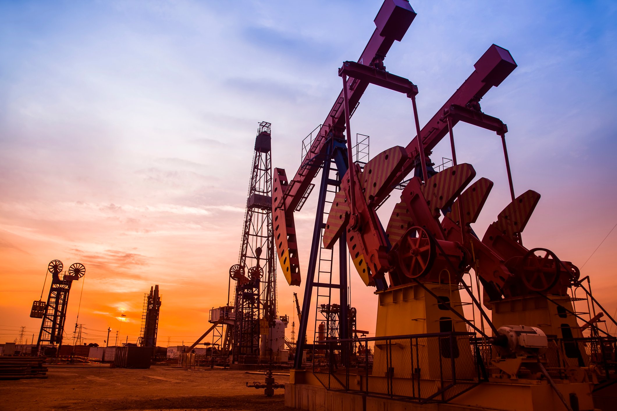 An oil-pumping unit with the sun just over the horizon in the background.