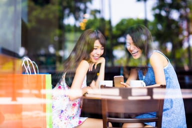 Two Young Asian Women Laughing Over Mobile Phone