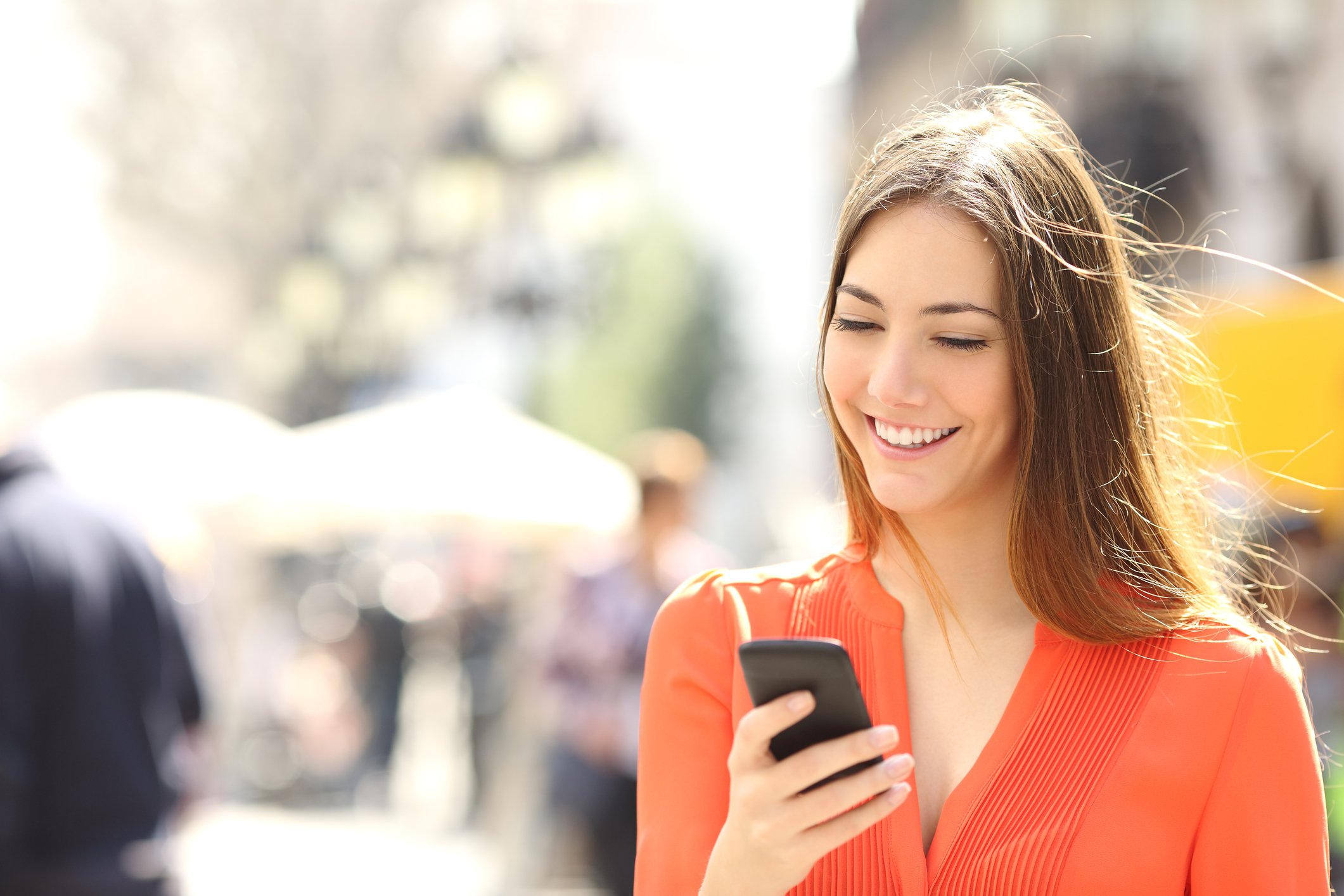 A woman smiles as she looks at her smartphone