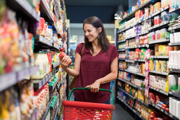 Woman lifting a jar off a supermarket aisle