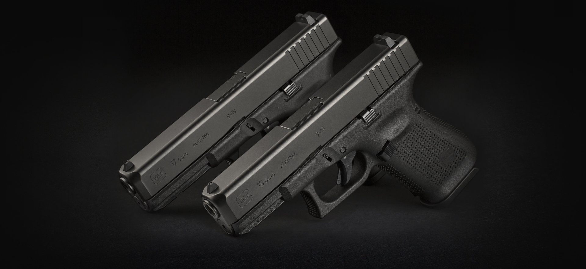 Two Glock 19's against a black background.