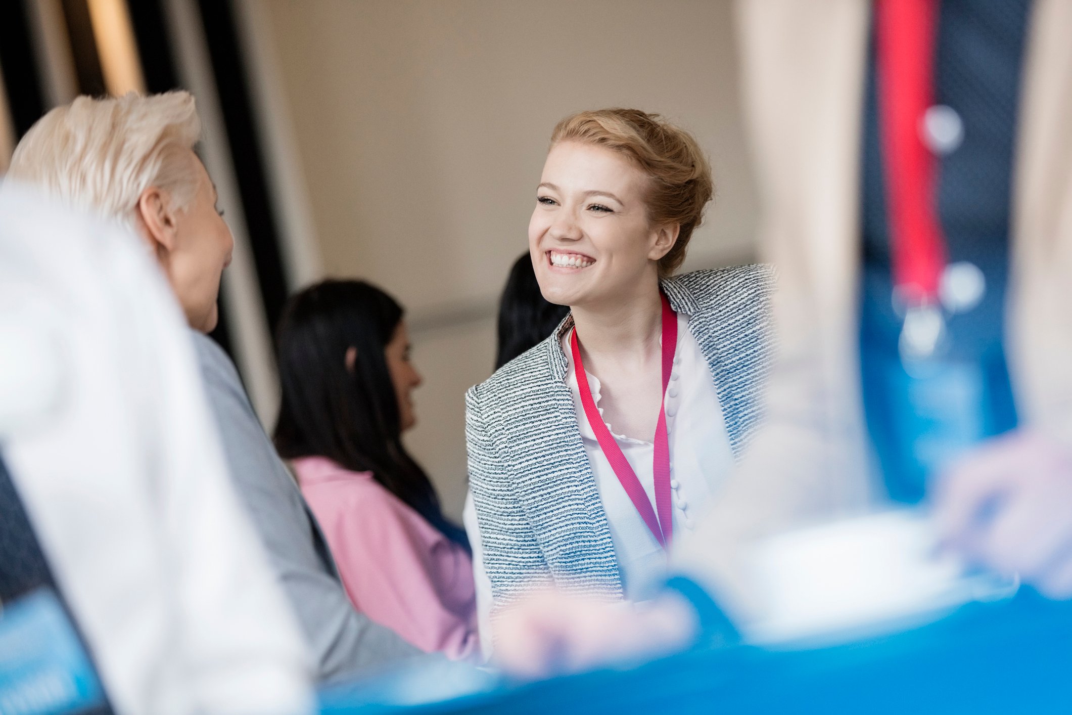 Smiling woman wearing a badge, talking to another woman