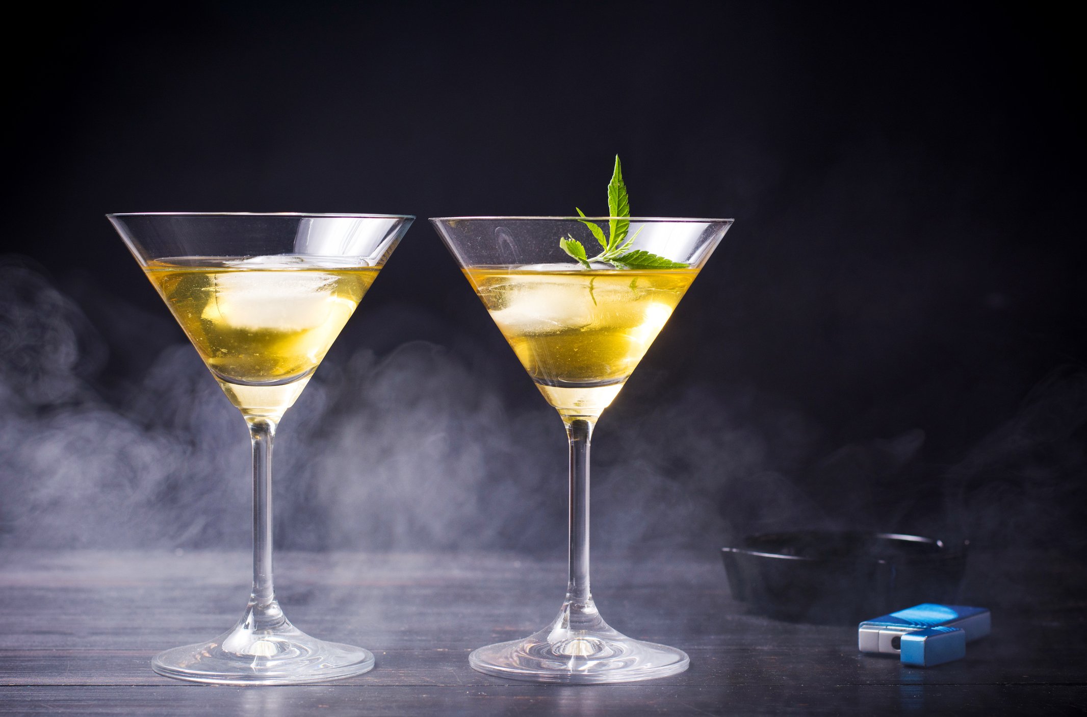 Two cocktail glasses with one containing a marijuana leaf