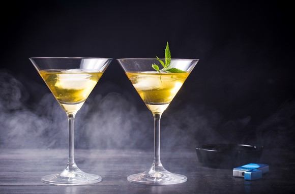 Two cocktail glasses with one containing a marijuana leaf