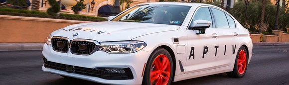 A white BMW sedan with Aptiv logos. 