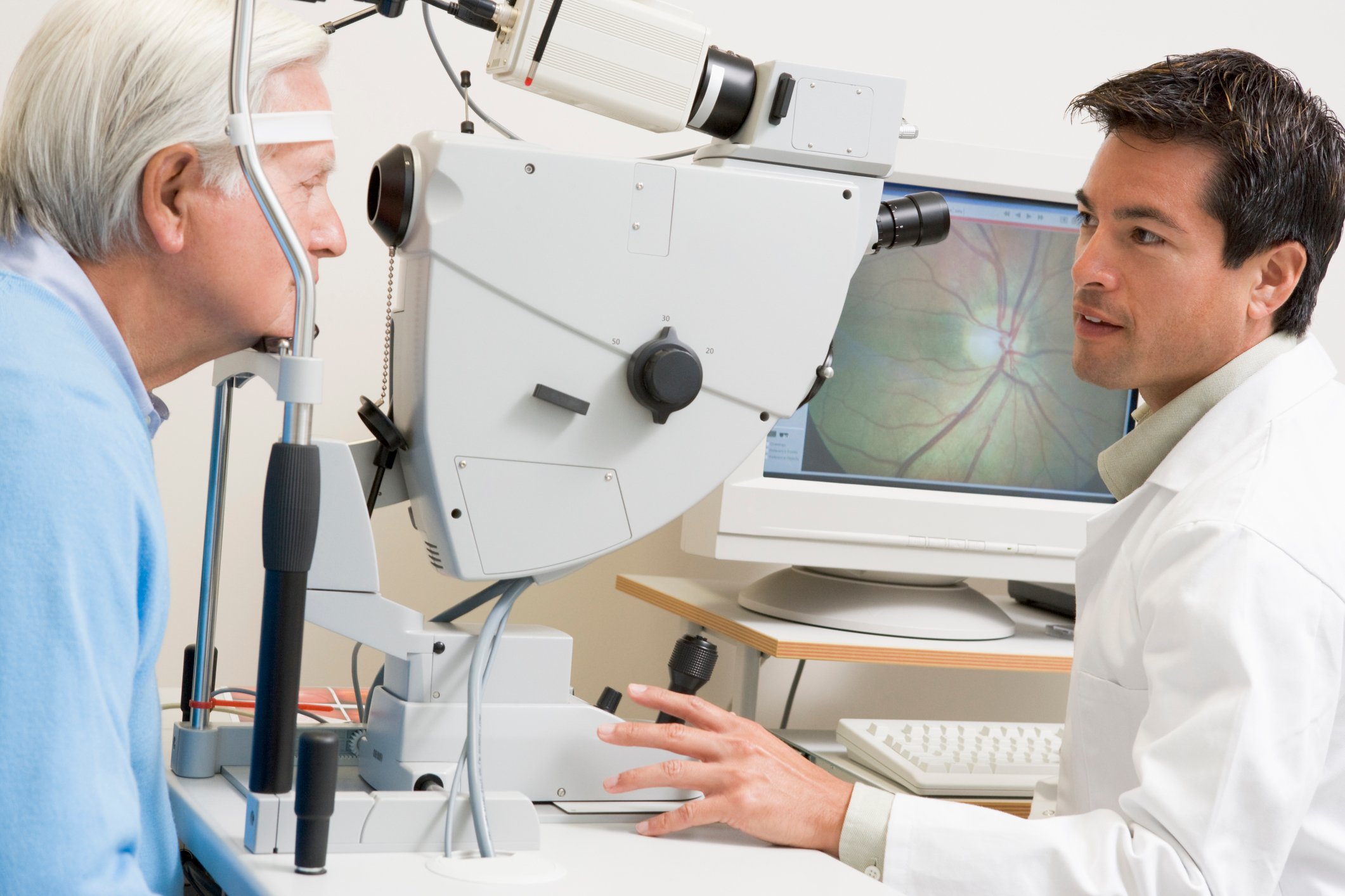An opthamologist looking at the eyes of an elderly man.