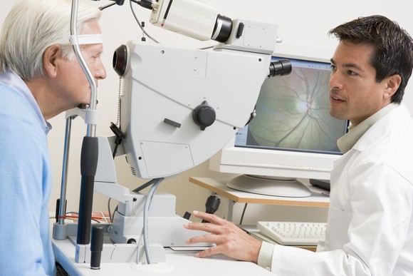 An opthamologist looking at the eyes of an elderly man.