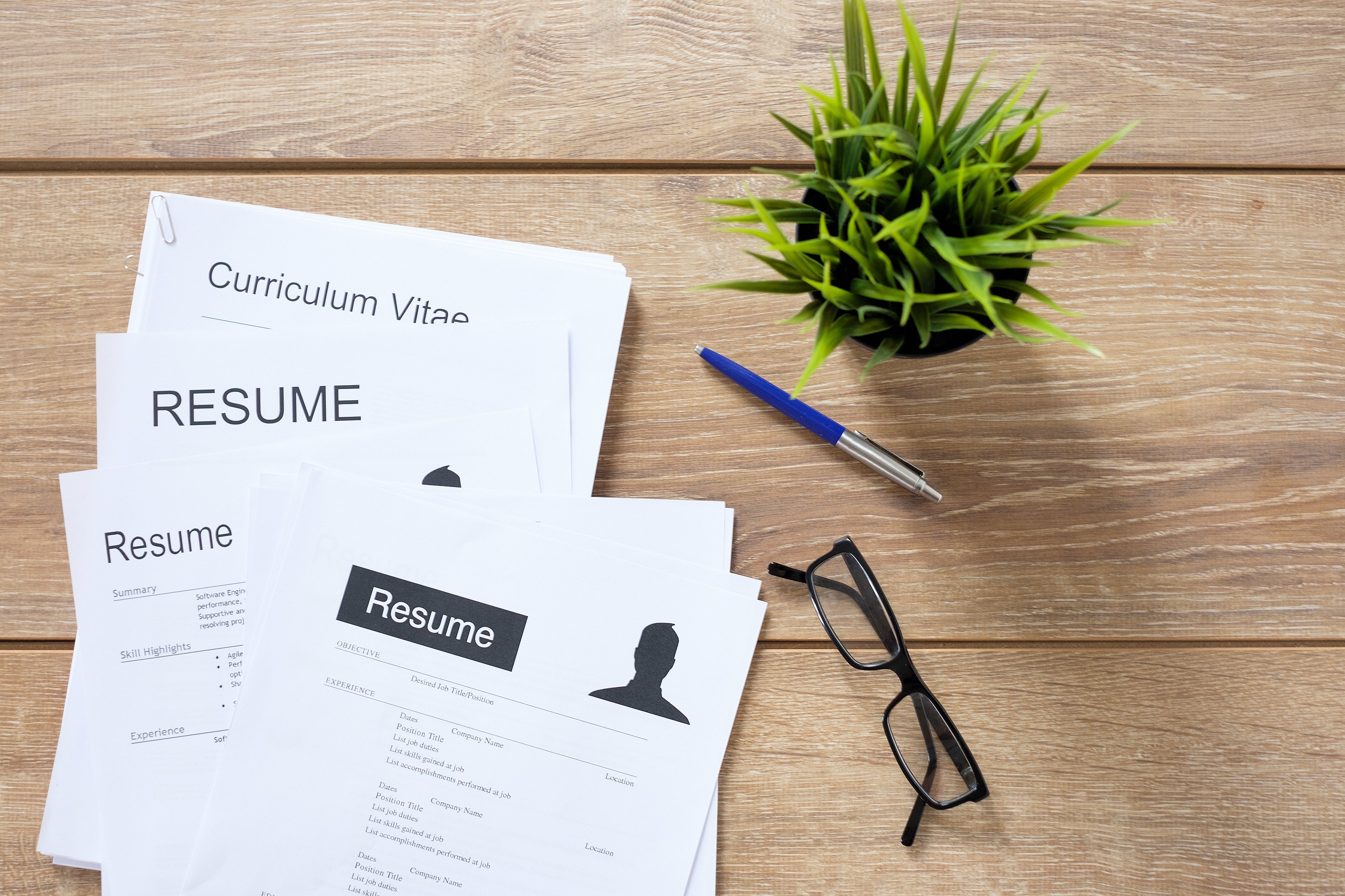 A pile of resumes sits on a table.