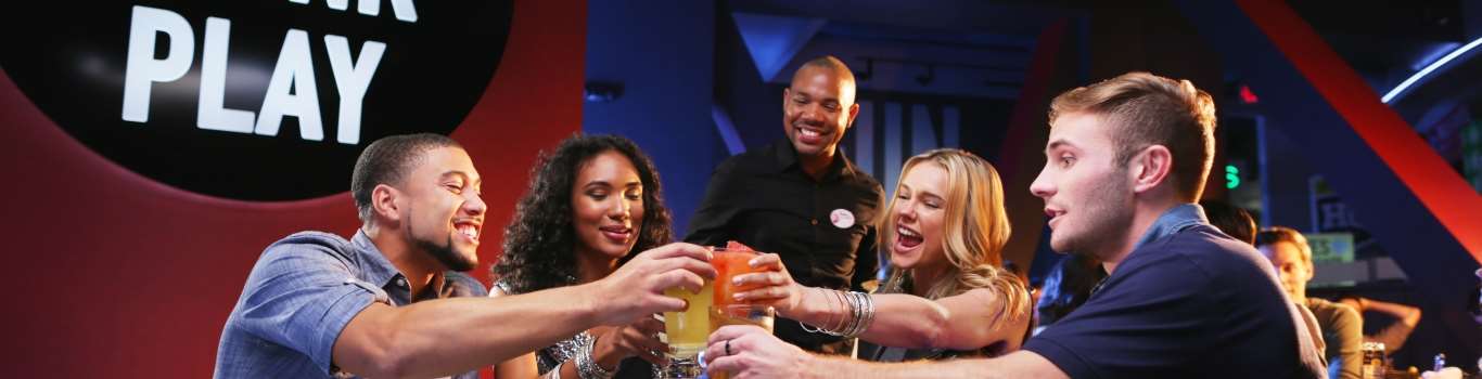 A group of raising beer glasses in a toast at Dave & Buster's.