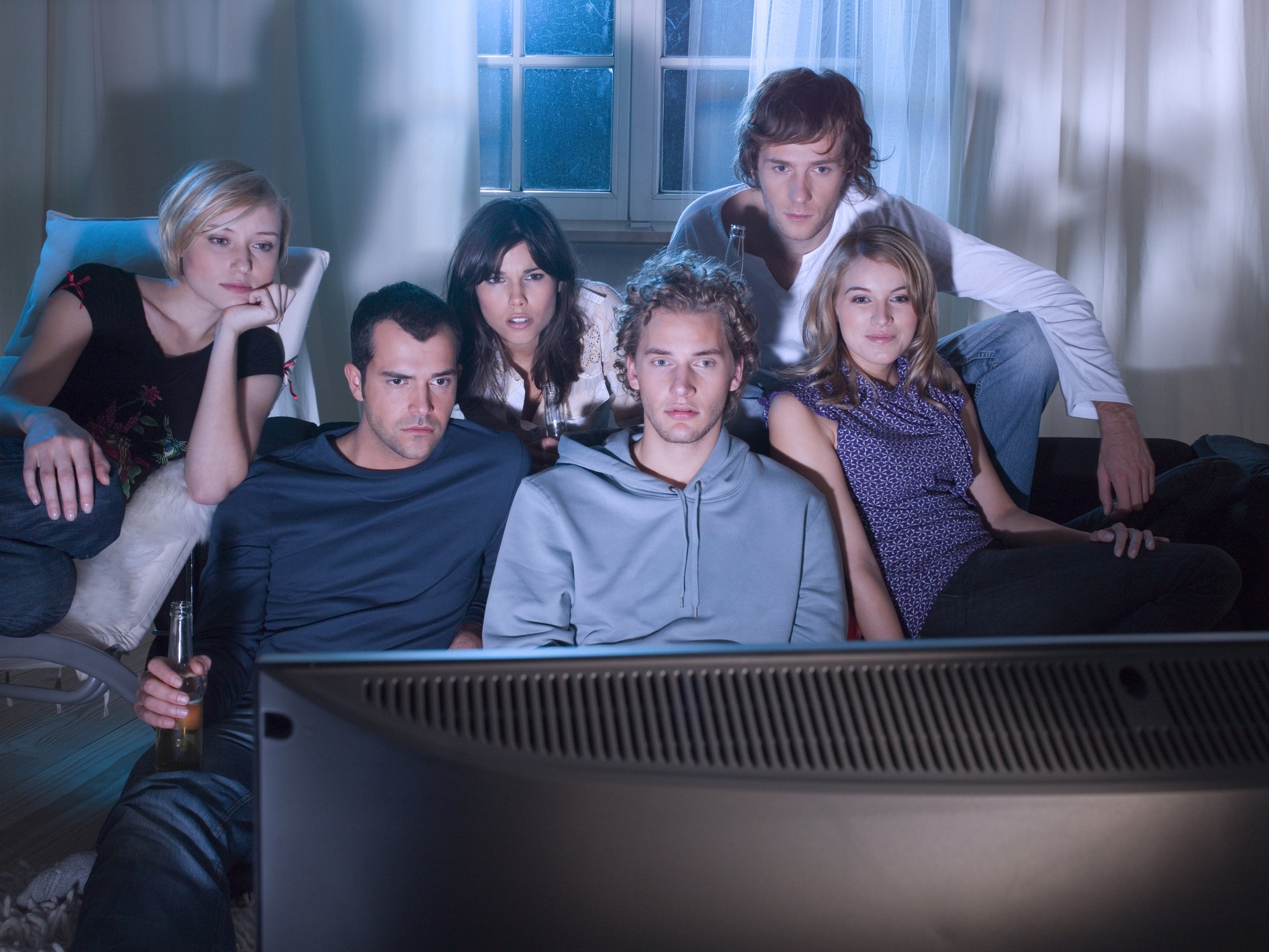 A group of young people watching TV together.