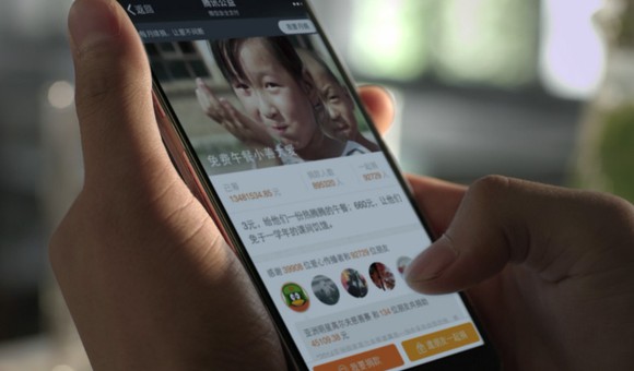 A closeup of someone using a smartphone on which one of Tencent's apps is showing.