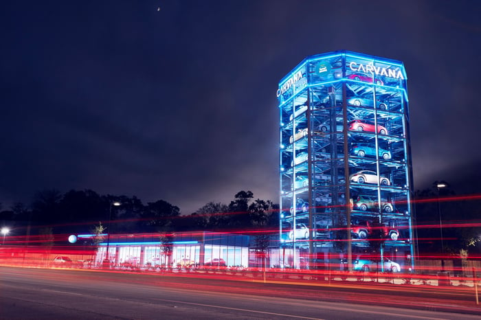 A Carvana vending machine, a glass-walled tower displaying cars, at night. 