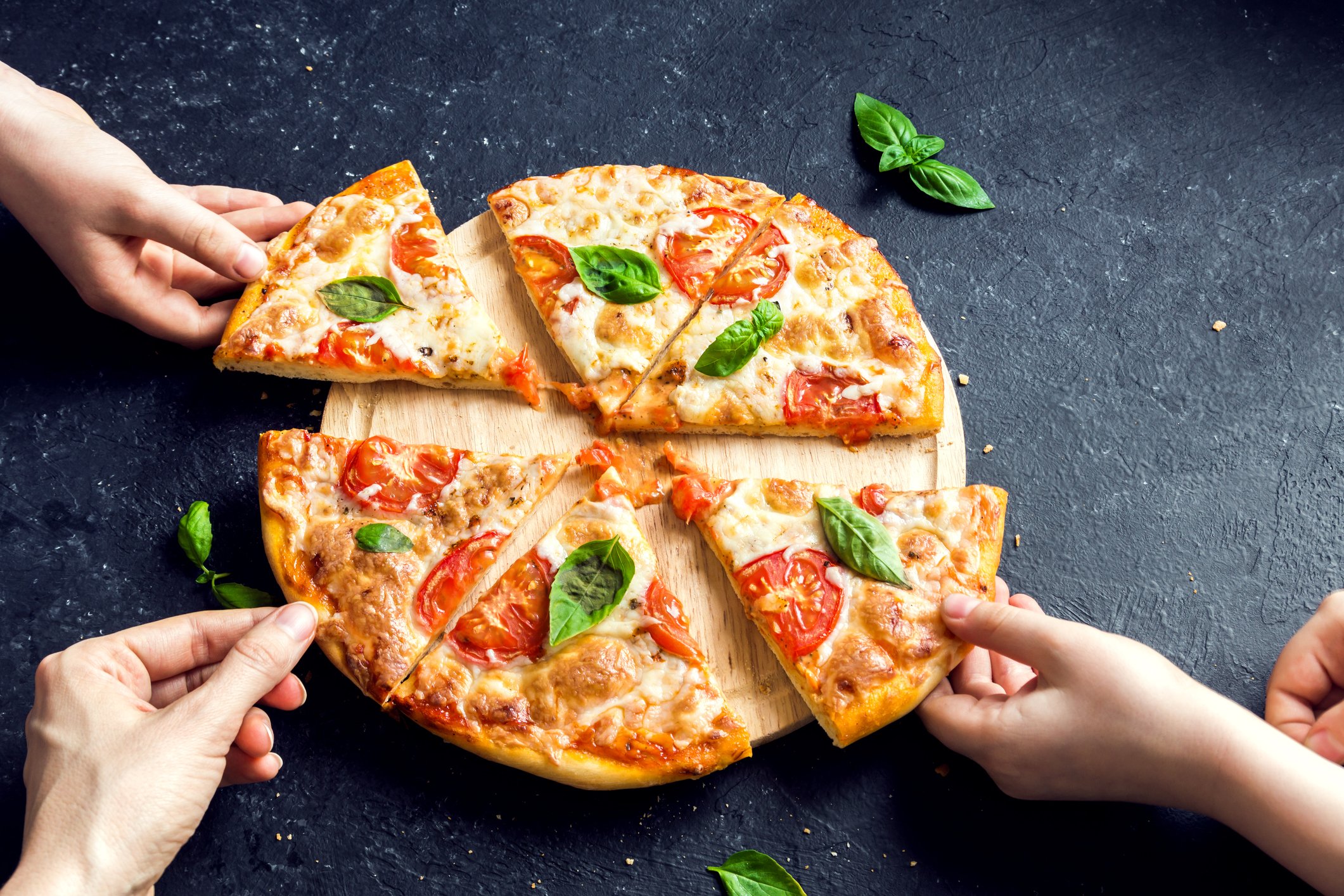 Hands grabbing slices of pizza