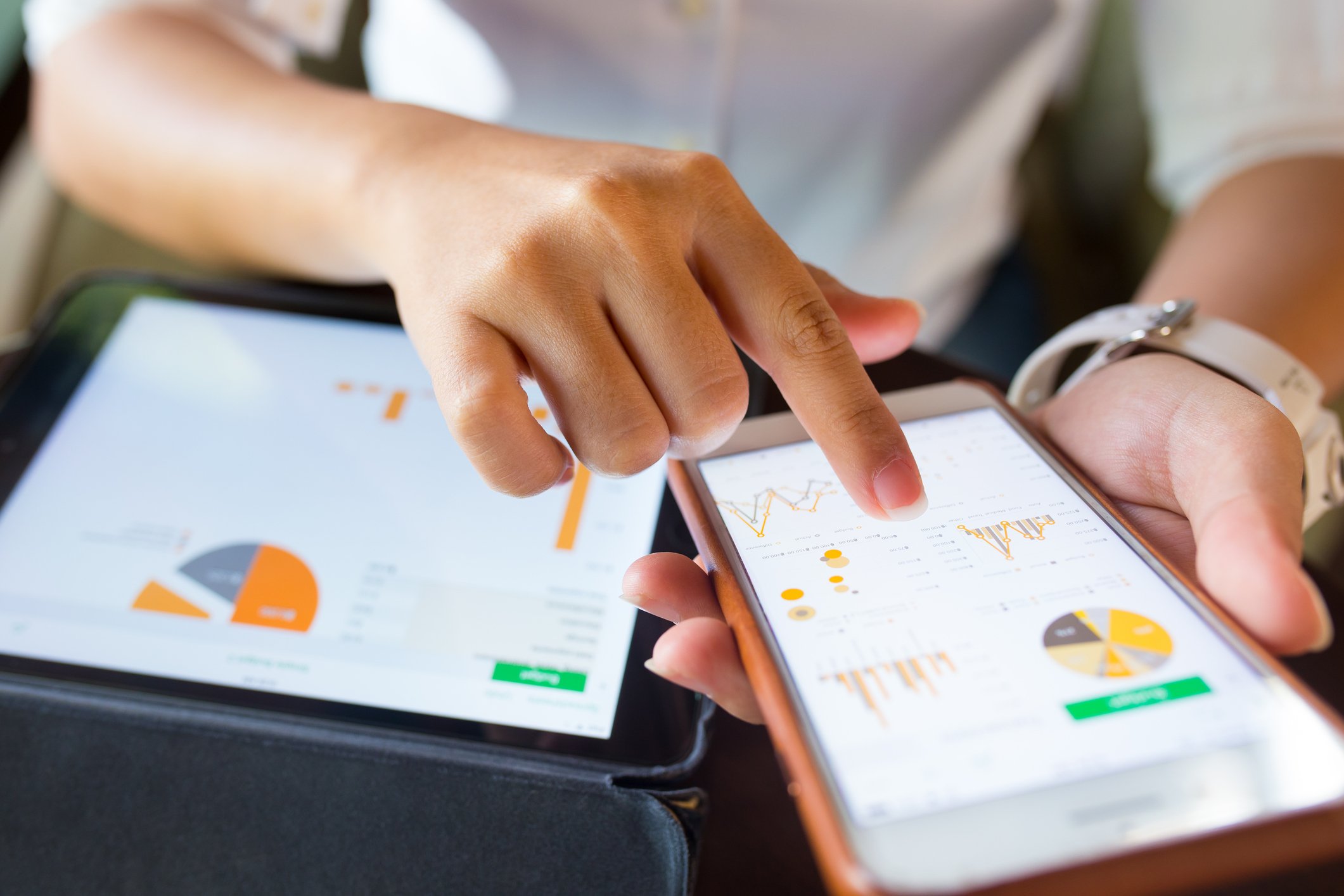 Woman pointing at charts on a smartphone and tablet.
