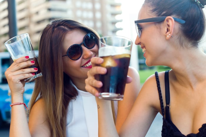 Two women drinking glasses of soda