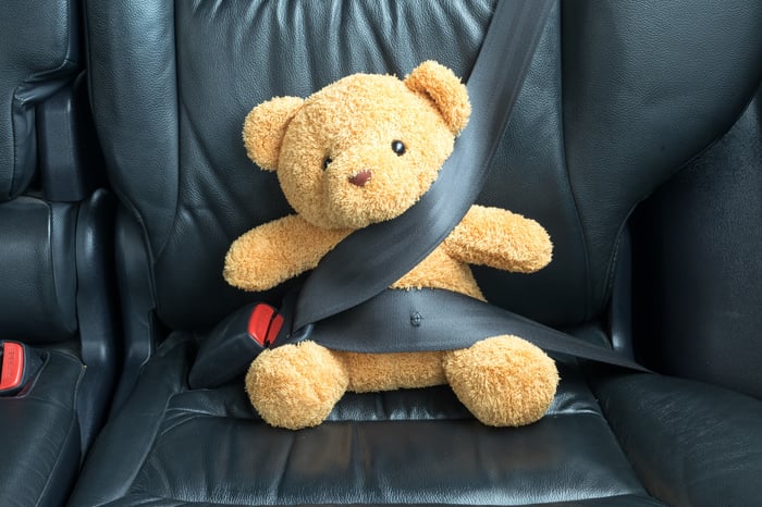 Stuffed bear in carseat with seatbelt around it.