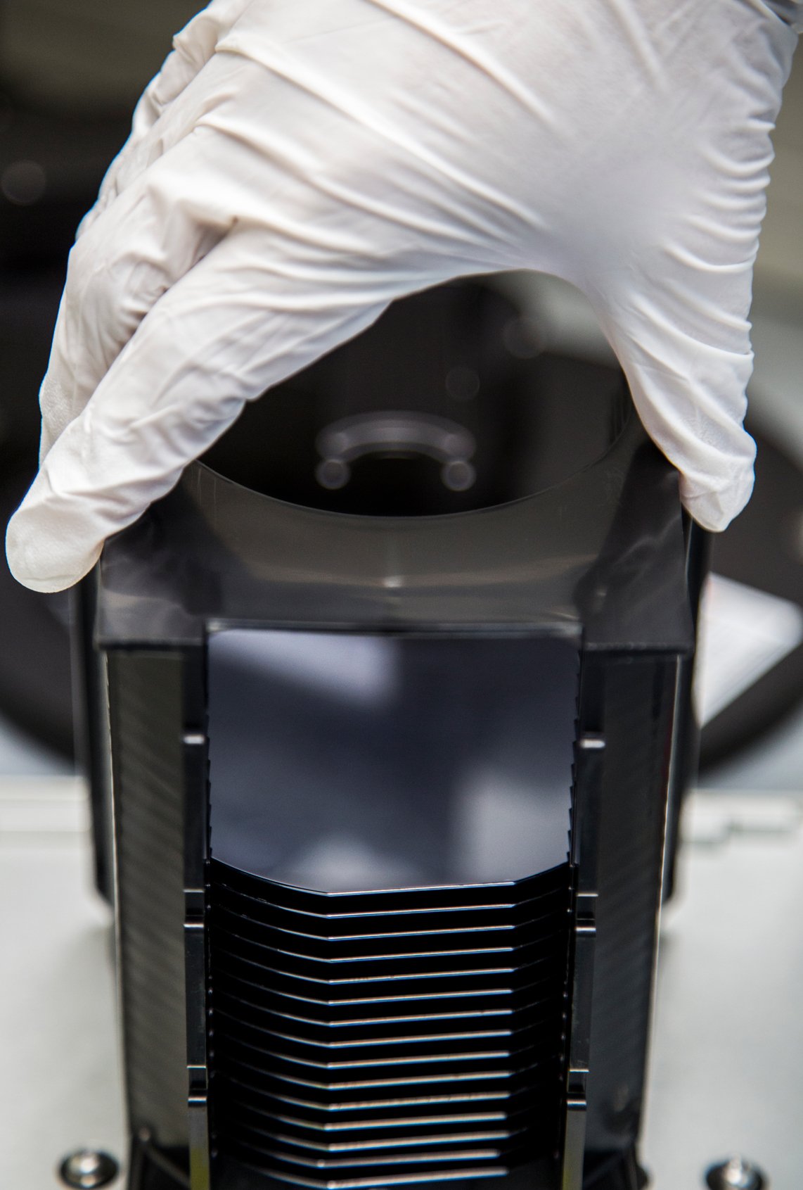 A technician's hand holding a stack of wafers