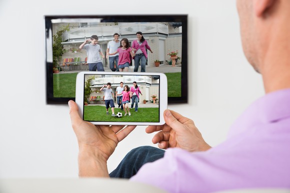 A man watching video on both a TV and a smartphone.