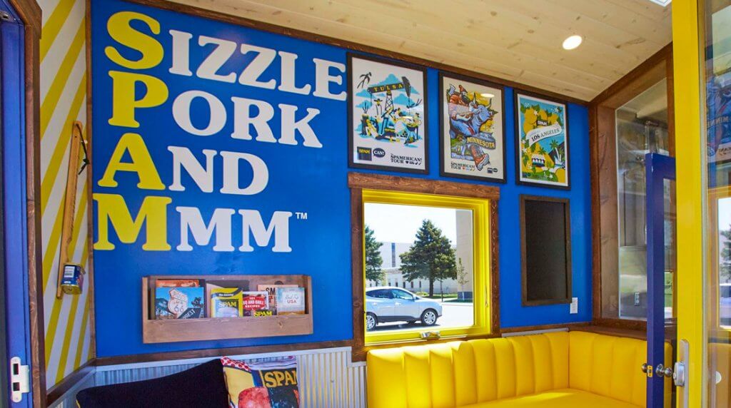 A wall in a tiny house shows the SPAM acronym "Sizzle Pork And Mmm"