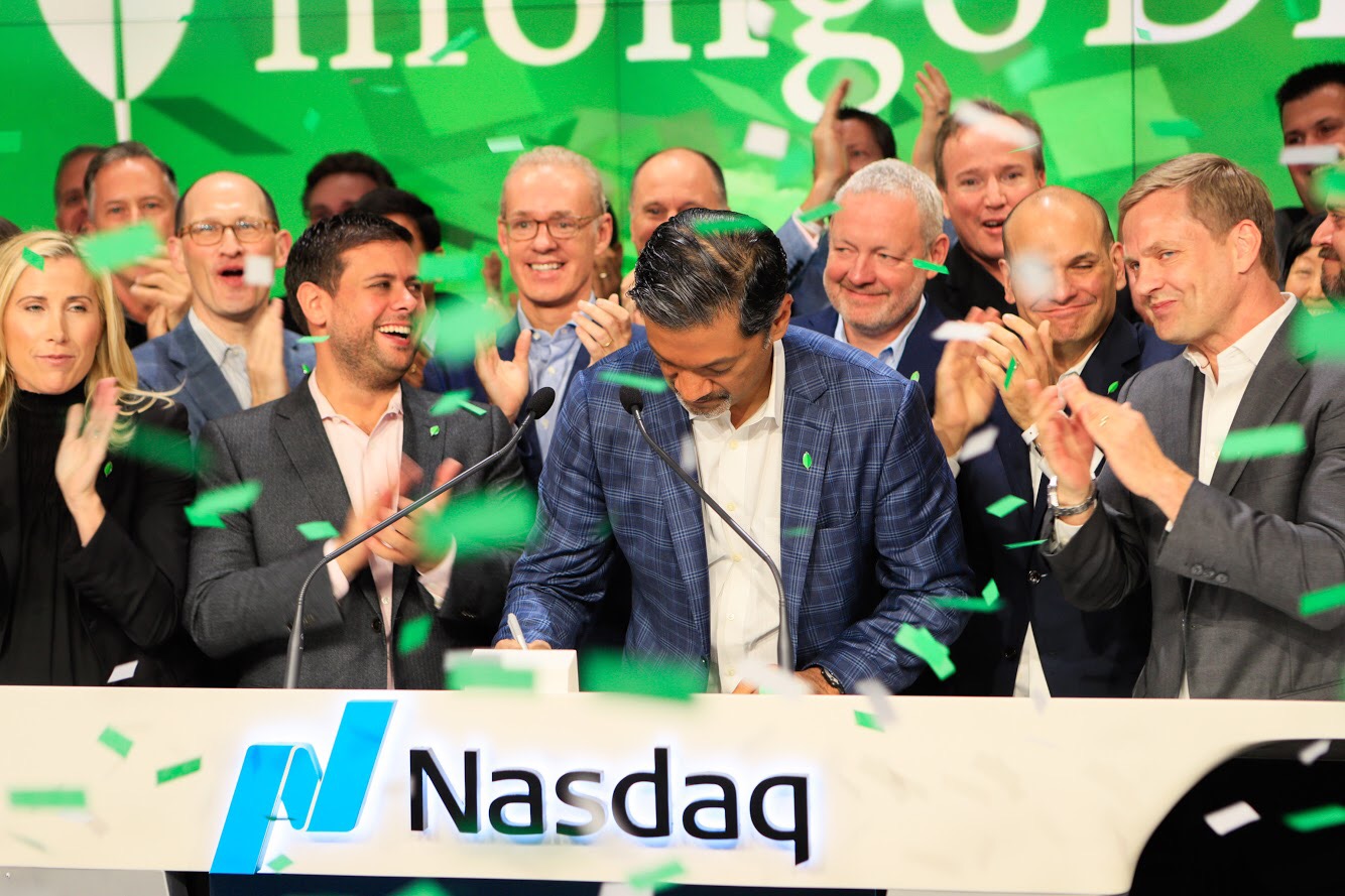 MongoDB CEO Dev Ittycheria and other members of the management team at the Nasdaq stock exchange as green confetti falls around them.
