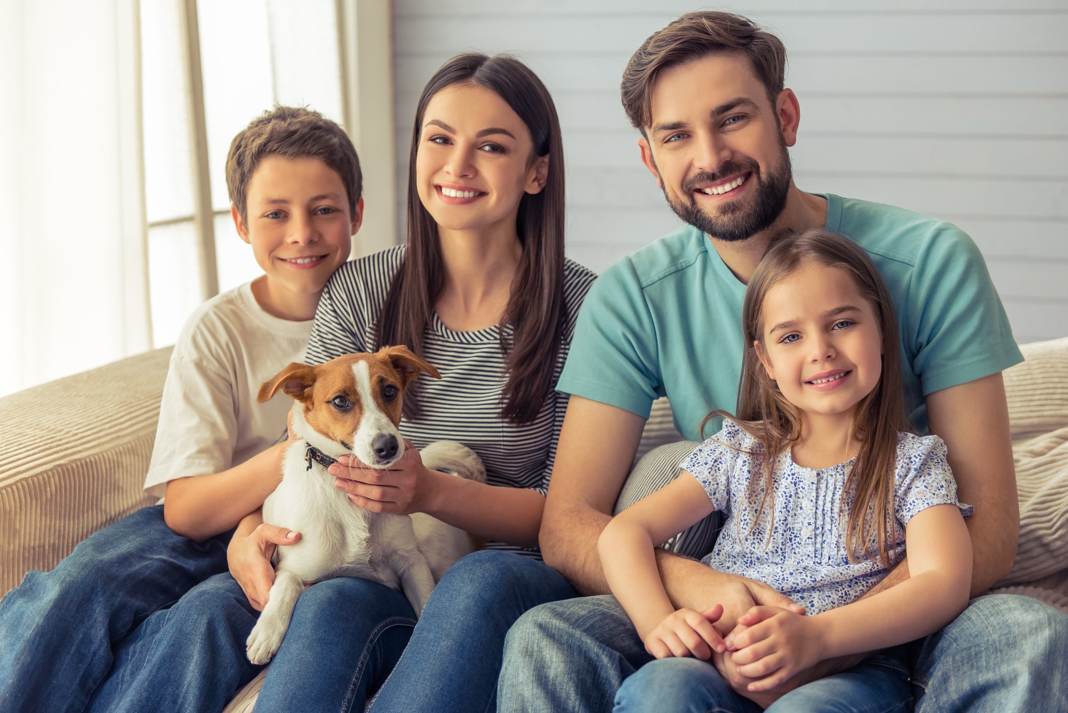 Young, smiling couple seated together with boy, girl, and dog