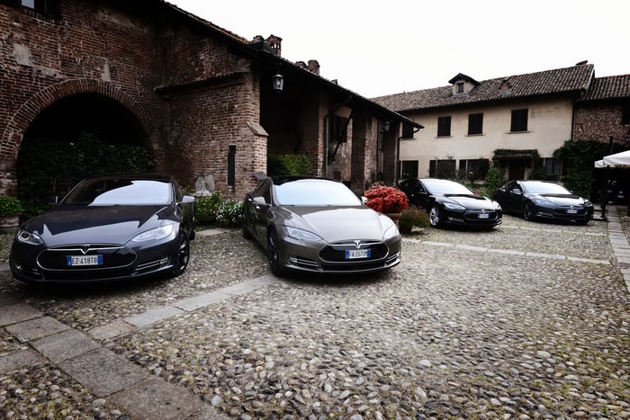 Four Tesla Model S Roadsters parked on a cobblestone driveway.