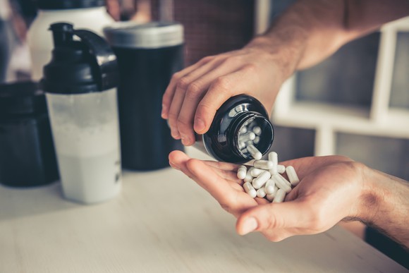 A man pours some pills into his hand.