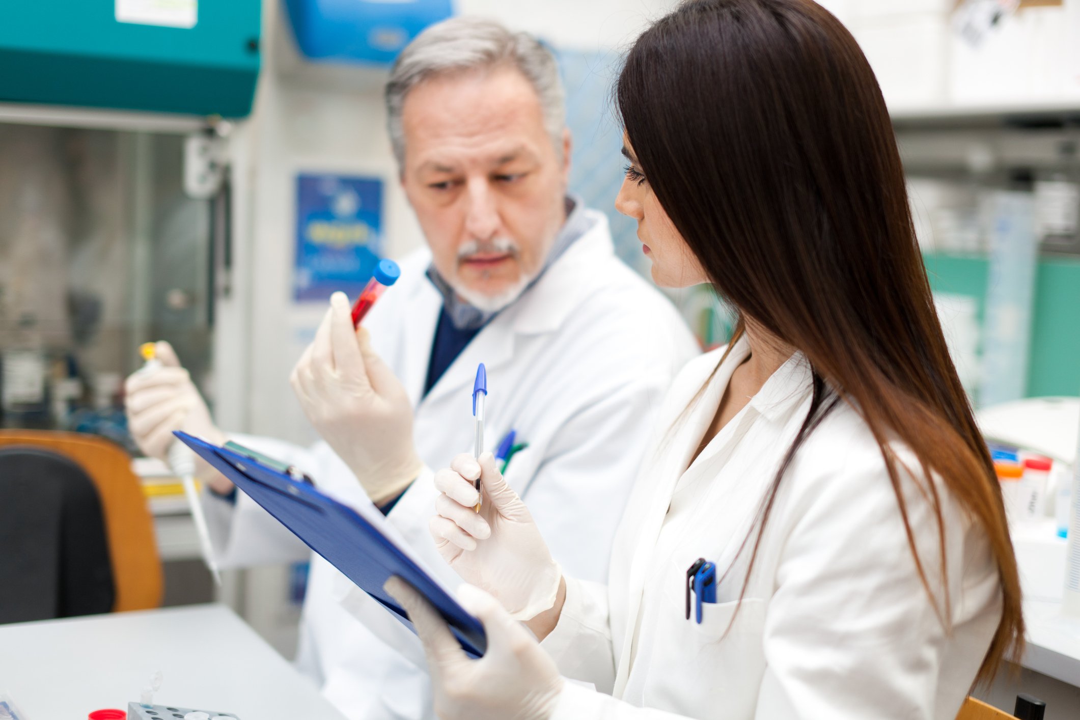 Scientists at work, reviewing data on a clipboard in a lab.