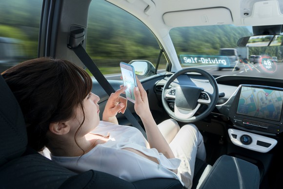 Woman sitting in driver's seat of car and reading on her phone.