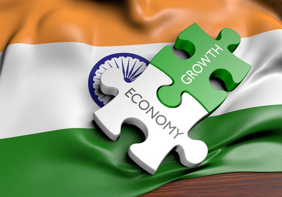 Two jigsaw pieces with economy and growth written on each against a backdrop of the Indian flag.