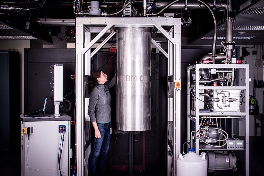 A woman standing next to an IBM Q prototype quantum system.