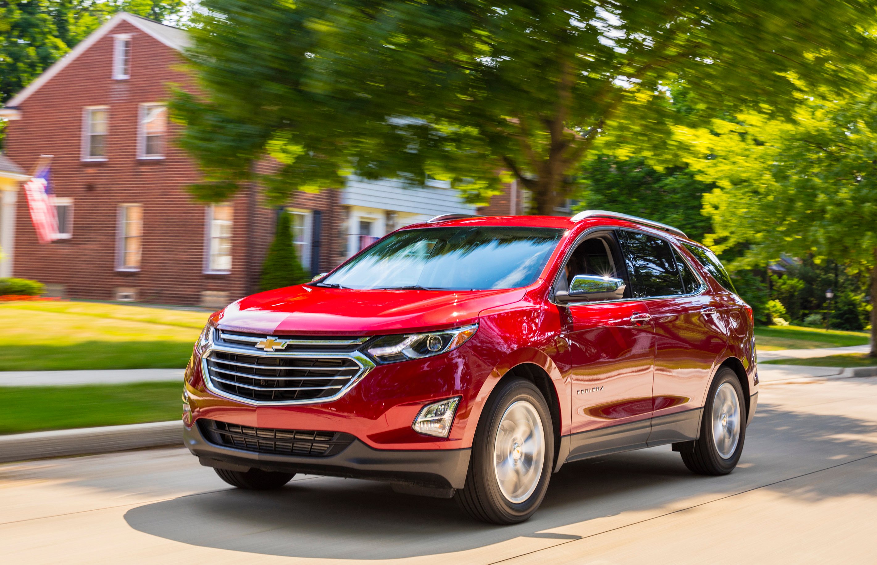 A red 2018 Chevrolet Equinox crossover SUV on a suburban street. 